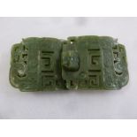 A Chinese green jade carved and pierced two part belt buckle with stylised mask clasp