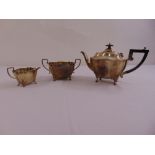 A silver three piece teaset shaped oval with angled handles on four scroll legs, Birmingham 1902 (