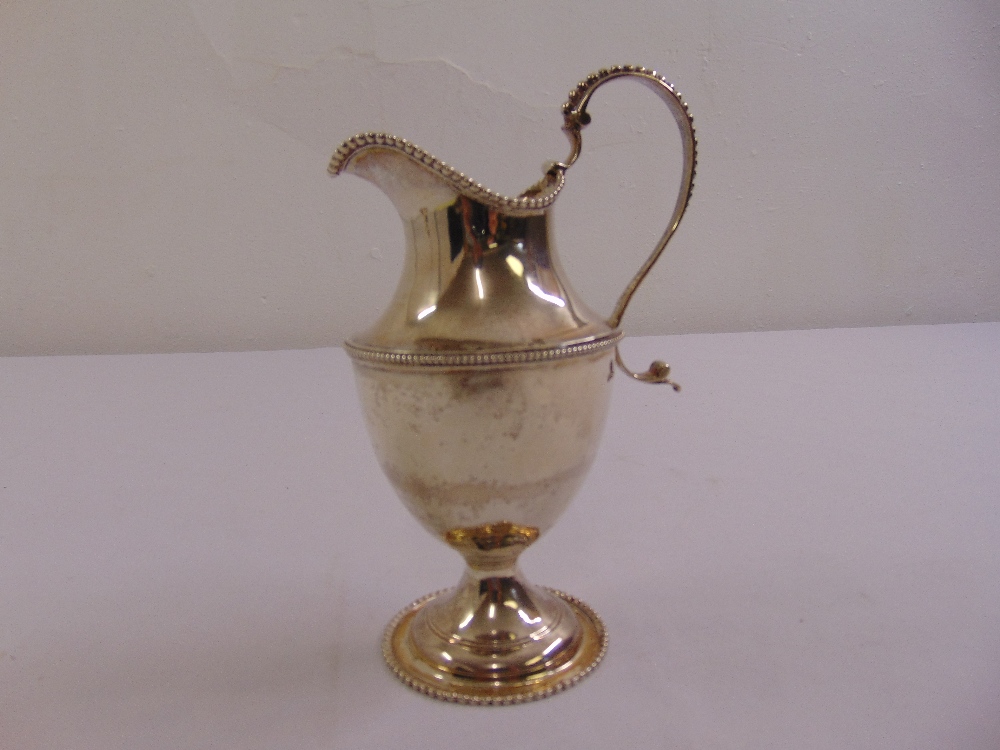 A George III silver cream jug, vase form with beaded borders, scroll handle on raised circular base,