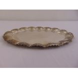 A continental white metal shaped oval tray chased with a raised border of scrolls and stylised