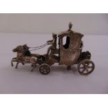 A continental white metal model of a horse drawn carriage, marks to base