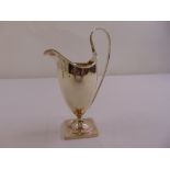A George III silver cream jug vase form with moulded border and ribbed loop handle on square base,