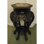 A Chinese hardwood plant stand on six supports, profusely carved with vegetation and leaves and