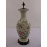 A Chinese baluster form lamp base decorated with flowers and leaves on a hardwood stand