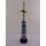 An Oriental blue and white cylindrical lamp base on hardwood stand