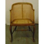 A mahogany bergere tub chair on four scroll legs