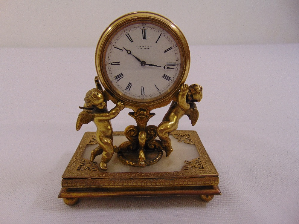 A Tiffany & Co gilded metal mantle clock, the circular dial supported by two putti on rectangular