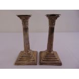 A pair of silver Corinthian column table candlesticks on stepped square bases with beaded borders,