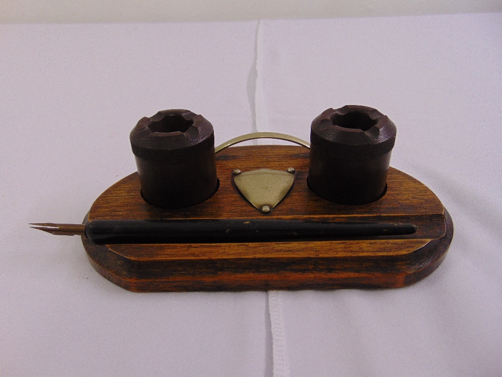 An early 20th century wooden pen stand of oval form with a nib pen