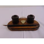 An early 20th century wooden pen stand of oval form with a nib pen