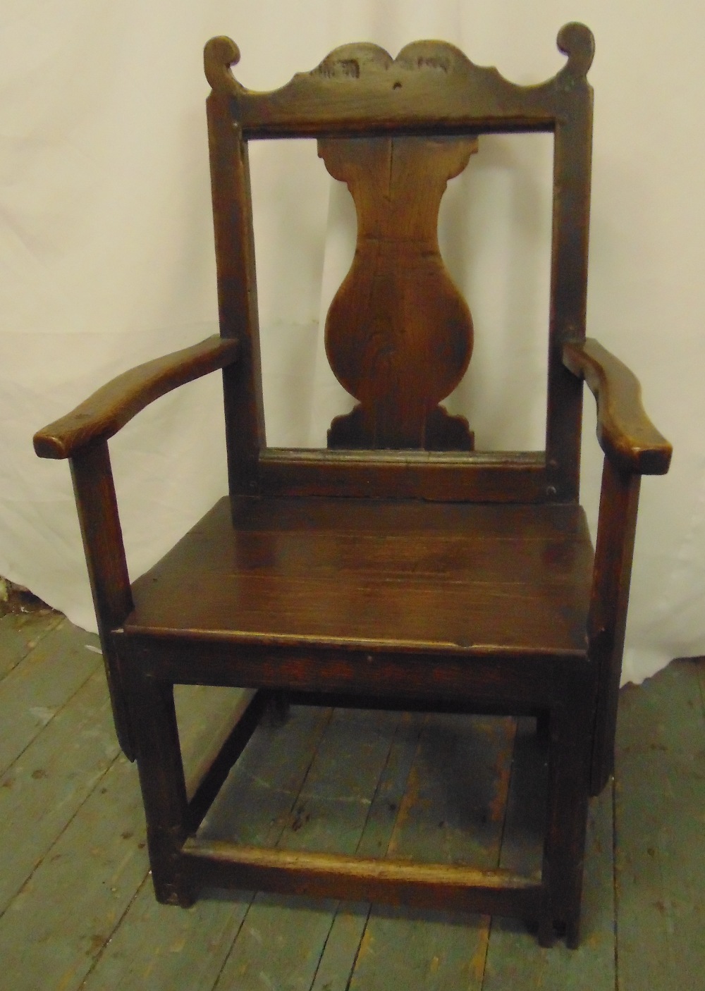 An early 18th century oak chair with central splat, open arms and canted square legs