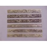 Six Oriental rectangular white metal picture weights chased with dragons and stylised forms