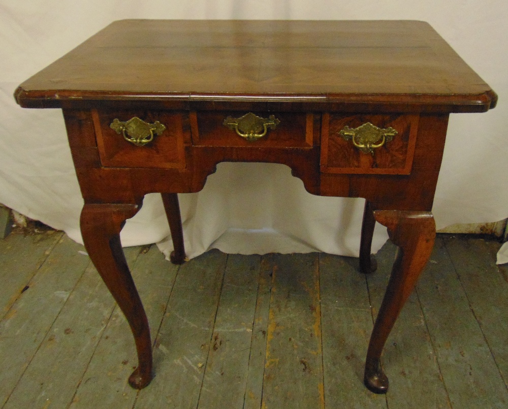 A Georgian rectangular walnut lowboy with three cross banded drawers, four cabriole legs with pad