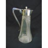 A silver mounted cut glass claret jug with scroll handle and hinged cover