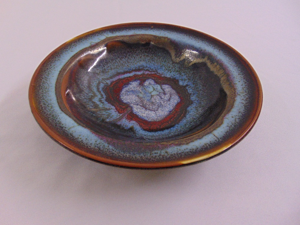 A circular ceramic studio dish, bronze and blue glaze, marks to the base