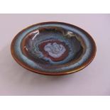 A circular ceramic studio dish, bronze and blue glaze, marks to the base