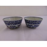 A pair of Chinese blue and white rice bowls decorated with scrolls and geometric forms