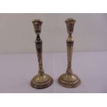 A pair of continental white metal table candlesticks tapering cylindrical form with floral and