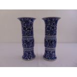 A pair of 19th century Chinese blue and white cylindrical vases decorated with flowers and scrolls