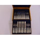 An oak cased set of silver and mother of pearl dessert knives and forks, for a twelve place setting,