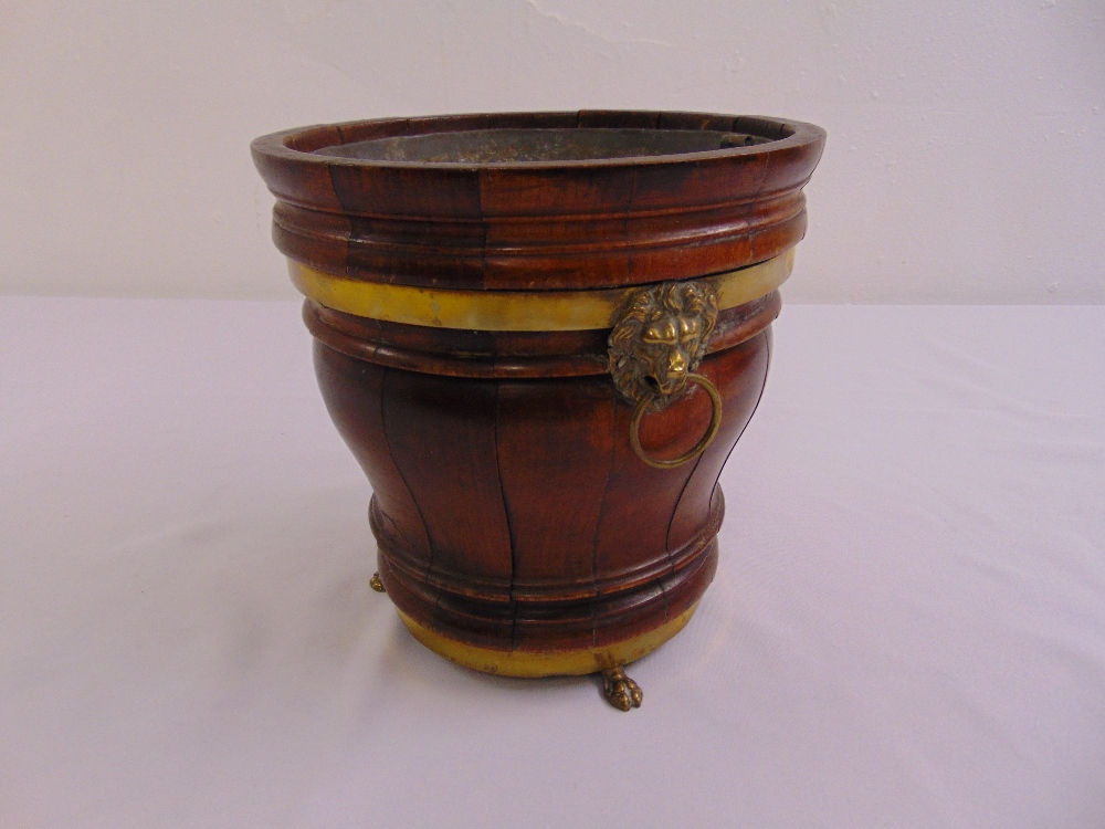 A tapering circular brass and wood planter with brass lion mask ring handles and brass feet circa