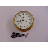 A brass ships style circular wall clock, white enamel dial with Roman numerals, two train