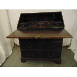 A 19th century rectangular oak bureau, the hinged top above three drawers with brass handles, all on
