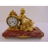 A French 19th century gilt metal mantle clock, flanked by a figurine of a seated lady, on