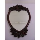 A carved hardwood heart shaped wall mirror