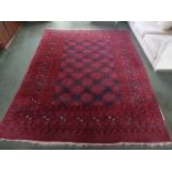 A Persian red ground wool carpet with repeating geometric motif and border, 277 x 217cm