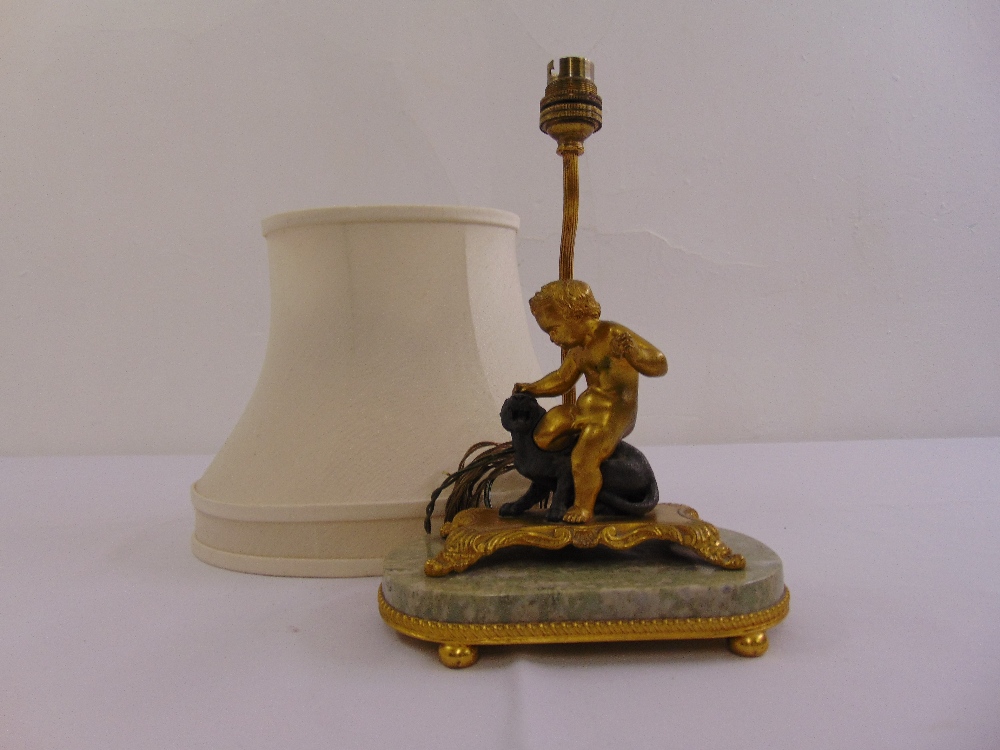 An early 20th century gilt metal and marble table lamp with a cast figurine of a putti fighting a