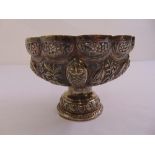 An Indian white metal bowl chased with rural scenes on raised circular base