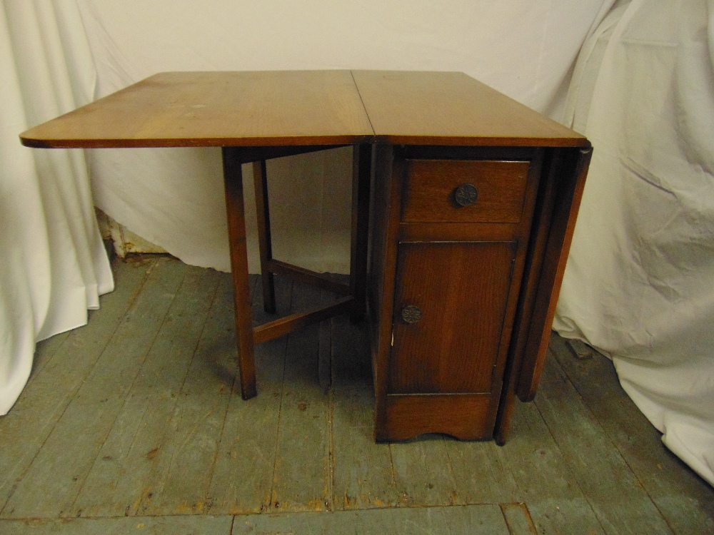 An oak utility desk with hinged doors to cupboards and two drawers