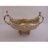 A continental white metal table centre piece, oval form with scrolling side handles surmounted by