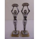 A pair of chrome Art Deco style figurines of ladies with arms raised on rectangular onyx bases,