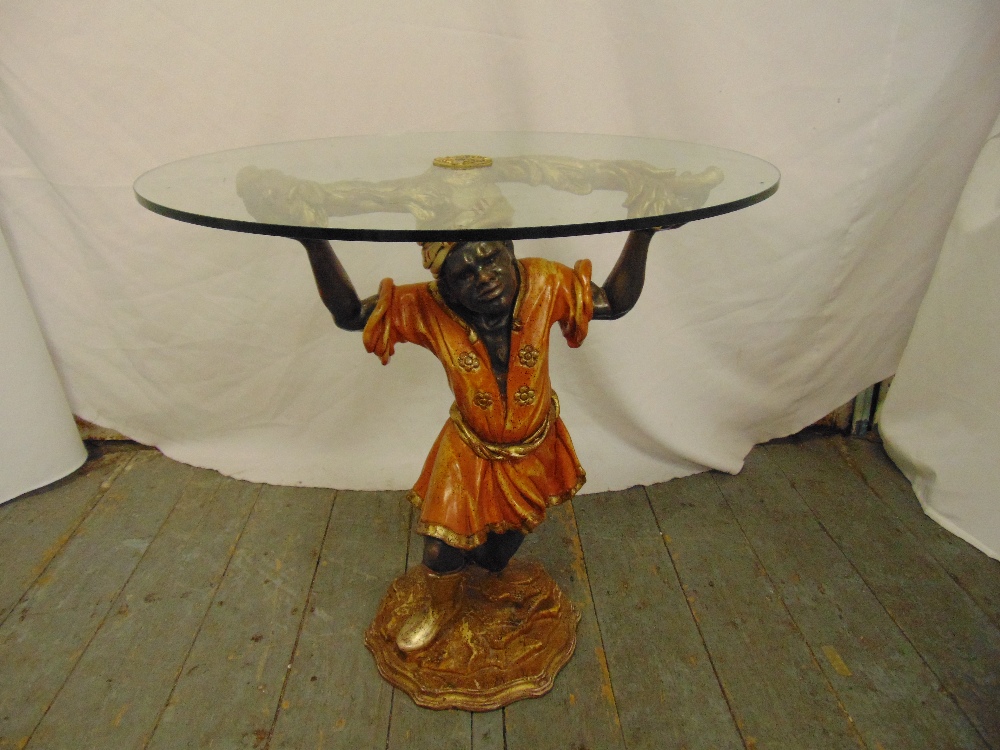 A Florentine circular glass side table supported by a kneeling Blackamoor on shaped circular base