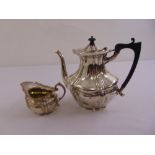 A silver coffee pot of fluted oval form with raised hinged cover, London 1920 and matching cream