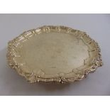 A Victorian silver salver shaped circular with shell and leaf border on three shell chased bracket