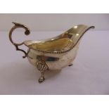 A silver sauce boat, shaped oval with gadrooned border, leaf capped double scroll handle on three