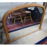A modern pine framed arched top over mantel mirror