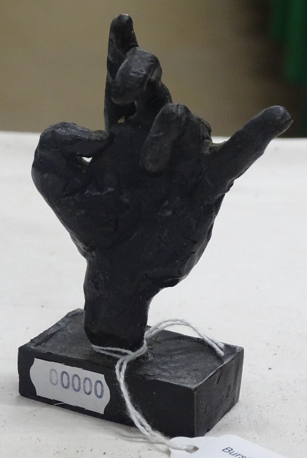 A small bronze sculpture of a hand.
