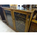 An oak bookcase with 2 lead light glazed doors, wi