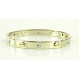 A 9ct white gold hinged bangle in the manner of Ca