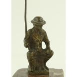 A patinated bronze figure of a man fishing, colour