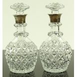 A pair of small cut-glass decanters with silver co