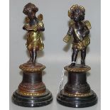 A pair of reproduction bronze cherubs on marble ba