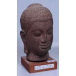 An Angkor Wat style ceramic Buddha head on wood pl