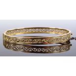 A 15ct gold hinged bangle, with pierced scroll wor