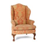 Georgian style upholstered wing armchair, upholstered throughout in figured salmon pink fabric,