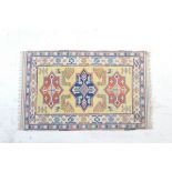 Caucasian woollen rug, the ochre field centred with three star form medallions in blue and red,